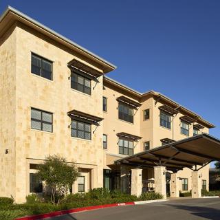 A modern commercial building with a stone facade and large windows under a clear blue sky.
