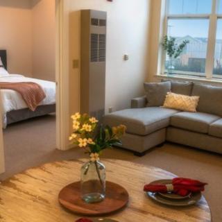 A cozy living space with a sofa, coffee table, and a view into the adjoining bedroom.
