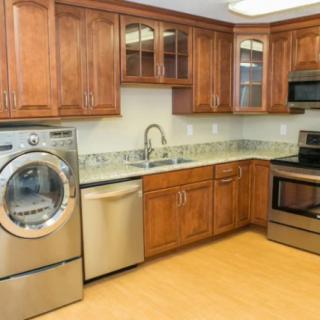 A modern kitchen with wooden cabinets, stainless steel appliances, and a granite countertop.