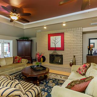 A cozy living room with elegant furniture and decor, featuring a fireplace and colorful artwork.