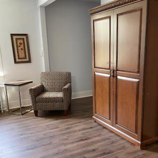 A cozy room featuring a comfortable chair and a wooden cabinet.