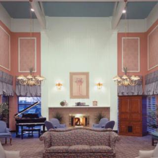 A classic style living room with high ceilings, featuring a grand piano and a fireplace, decorated in pastel colors.