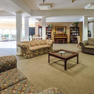A spacious living room with patterned sofas, a wooden coffee table, and bookshelves by the fireplace.