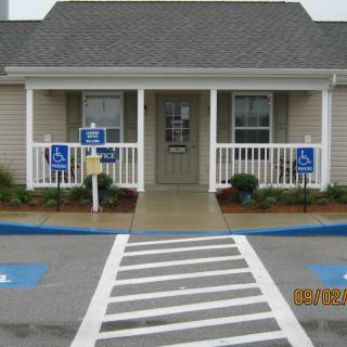 A small building with a front porch, featuring handicap parking and an accessible entrance.