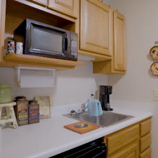 A compact kitchen featuring wooden cabinets, a microwave, and a coffee maker on the countertop.