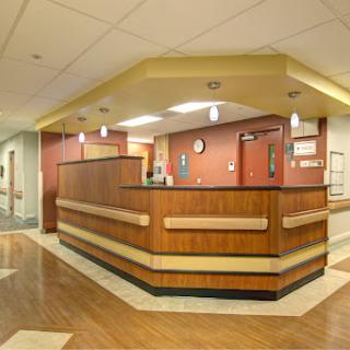 A modern hospital reception area featuring a wooden front desk and warm lighting.