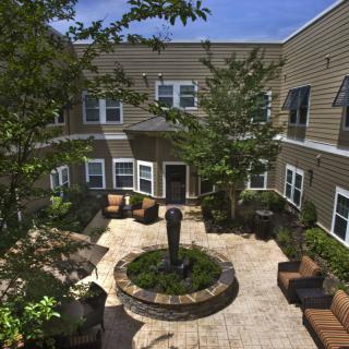 A cozy courtyard with a central fountain, surrounded by apartment buildings and outdoor seating.