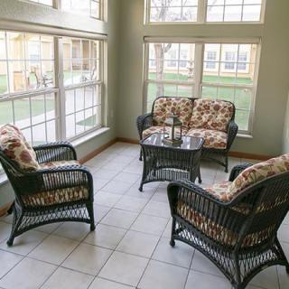 A cozy sunroom featuring wicker furniture and ample natural light streaming through large windows.