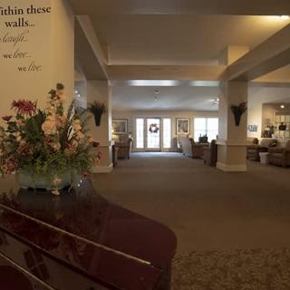 A spacious lobby with a piano and floral arrangement, leading to a well-lit hallway.