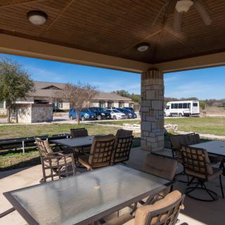 Outdoor patio area with tables and chairs under a covered pavilion.