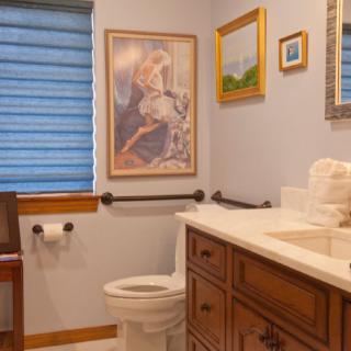 A cozy bathroom with artwork on the walls, featuring a toilet, sink, and mirror.