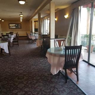 A quiet restaurant dining area with tables and chairs near large windows.