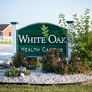 Entrance sign for White Oaks Health Care, surrounded by landscaped gardens.