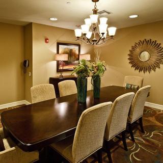 A stylish dining room featuring a dark wooden table, surrounded by upholstered chairs and illuminated by an elegant chandelier.