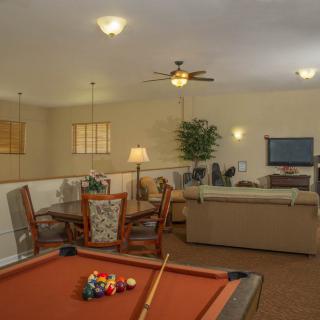 A cozy game room with a pool table, seating area, and ceiling fan.