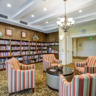 A cozy library reading area with striped armchairs and bookshelves.