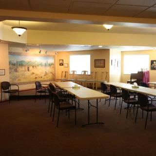 A well-lit meeting room with conference tables, chairs, and a mural on the wall.