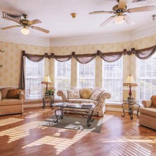 A spacious living room with large windows, elegant furniture, and wooden flooring.