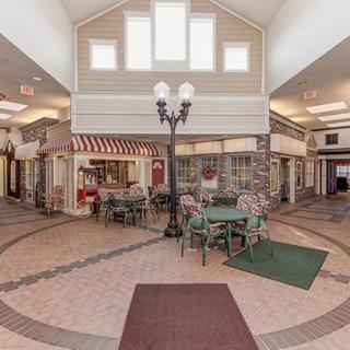 An indoor shopping area with tables, chairs, and decorative lighting.