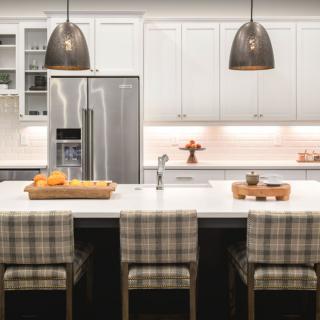 A modern kitchen with white cabinets, stainless steel appliances, and a central island with bar stools.