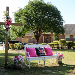 A serene outdoor space featuring a beautifully decorated bench and cross, perfect for reflection.