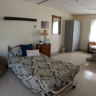 A clean and tidy hospital room with a bed and basic furniture.