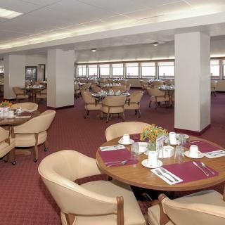 An empty dining area with round tables neatly set for guests.