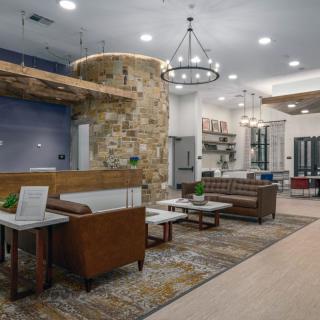 A modern lounge area featuring comfortable seating, elegant lighting, and a stylish stone wall with wood accents.
