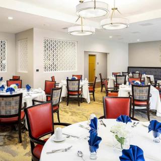 A well-arranged dining room with elegantly set tables and red chairs, ready for guests.