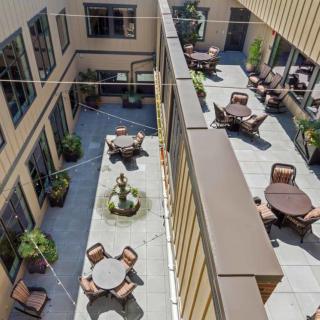 Aerial view of a courtyard featuring tables, chairs, a fountain, and surrounding buildings.