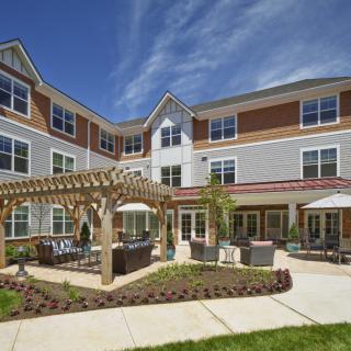 A modern residential building with outdoor seating and a pergola in the courtyard.