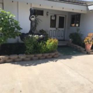 A cozy house entrance with a garden and driveway.