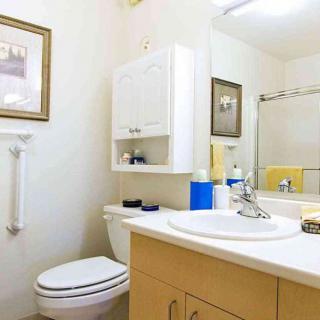 A clean and well-organized bathroom featuring a sink, toilet, and storage cabinet.