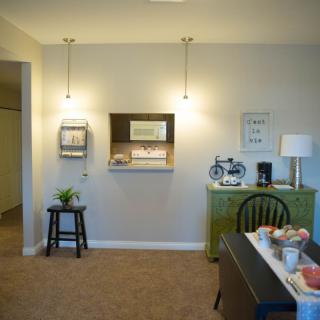 A cozy living room with modern decor, featuring pendant lights, a green cabinet, and a small stool.