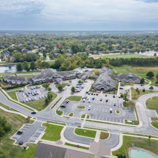 Aerial view of a spacious building complex surrounded by green landscapes and well-organized parking areas.