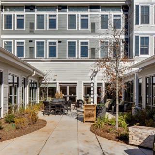 A modern courtyard with seating and landscaping surrounded by a multi-story building.