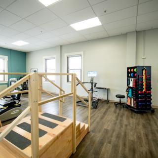 A rehabilitation room equipped with exercise equipment and a wooden staircase for physical therapy exercises.