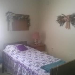 A cozy bedroom with a single bed, floral decor, and a small table lamp.