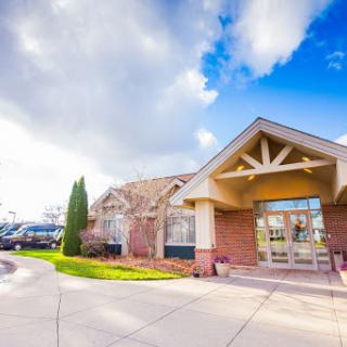 A welcoming building surrounded by a beautiful landscape under a partly cloudy sky.
