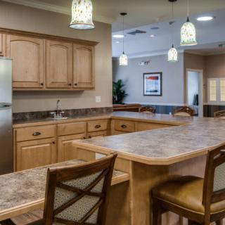 A modern kitchen with wooden cabinets, a large countertop, and stylish pendant lighting.