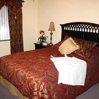 A well-decorated bedroom with a neatly made bed, stylish curtains, and a bedside lamp.