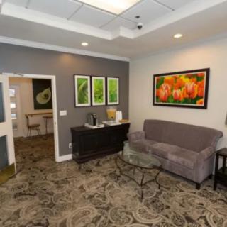 A cozy waiting room with a sofa, artwork on the walls, and a patterned carpet.