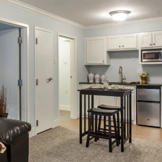 A modern apartment kitchen and dining area with a small table and stools.