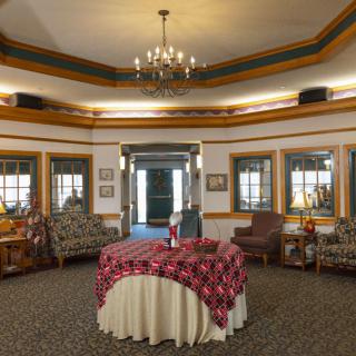 A vintage-style lobby area with a chandelier, surrounded by windows and furnished with comfortable seating.