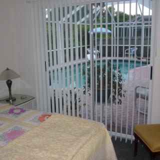 A cozy bedroom with a view of the pool through sliding glass doors.