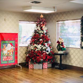 A beautifully decorated Christmas tree adorned with red and white flowers, surrounded by holiday decor.