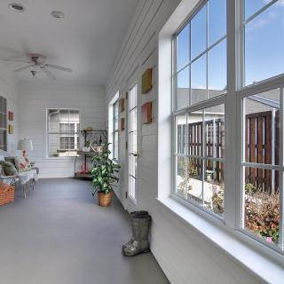 A bright and airy sunroom with large windows, indoor plants, and cozy decor.