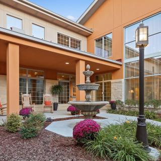 A well-maintained courtyard featuring a central fountain surrounded by flowering plants and modern architecture.