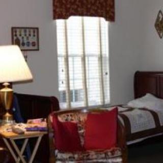 A cozy bedroom with a bed, lamp, and window, featuring decorative elements.