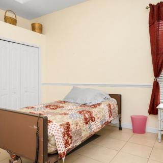 A cozy bedroom with a single bed, quilt, and red curtains.